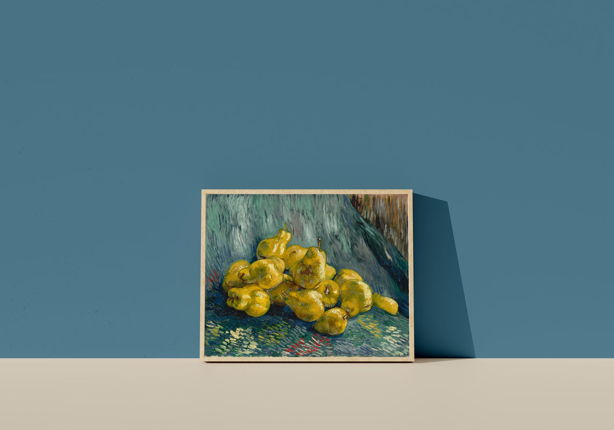 Framed art print of Still Life with Quinces by Vincent van Gogh, in a light wood frame leaning on a blue wall