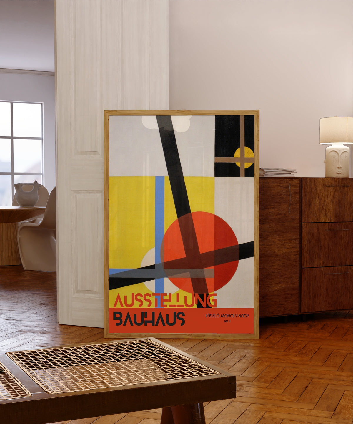 Framed art print of AM 2 by László Moholy-Nagy, in a light wood frame leaning in a warm room with a parquet floor