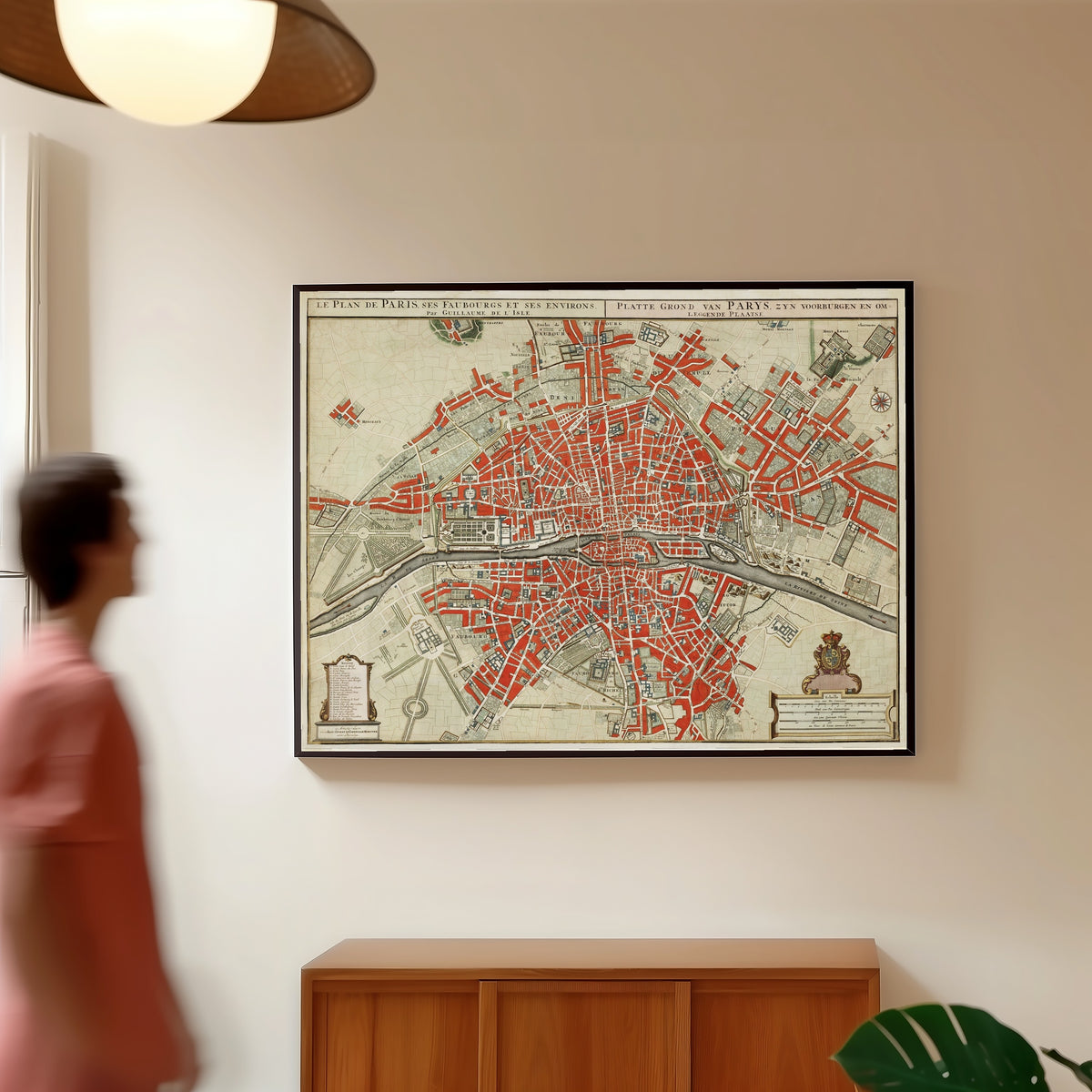 Framed art print of Le Plan de Paris, ses Faubourgs et ses Environs by Guillaume de l'Isle, in a slim black frame on a warm wall in a sunlit room