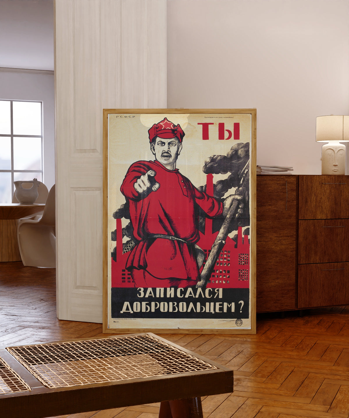 Framed art print of Have You Volunteered? by Dmitry Moor, in a light wood frame leaning in a warm room with a parquet floor