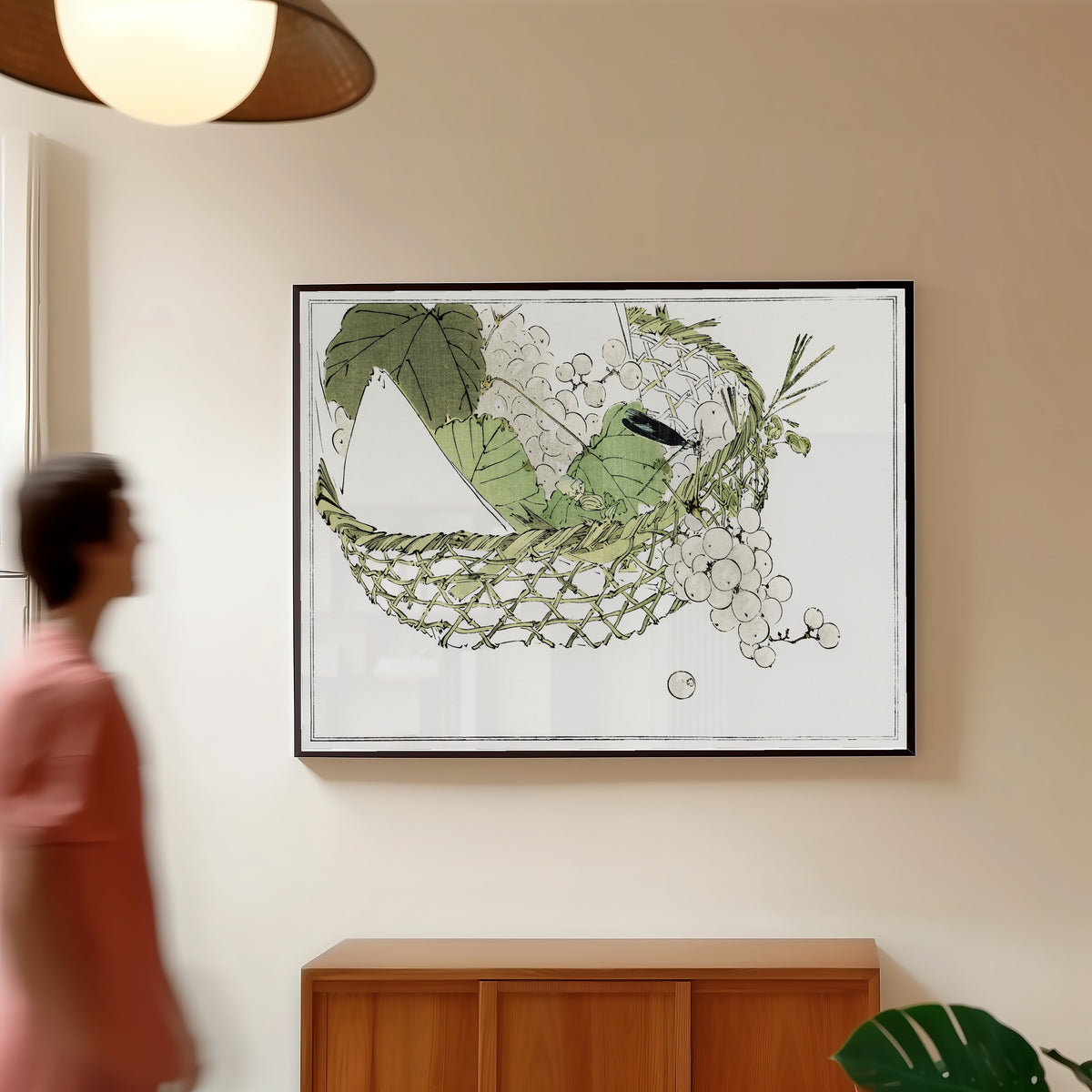 Framed art print of Basket of grapes from Seitei Kacho Gafu (1890–1891) by Watanabe Seitei, in a slim black frame on a warm wall in a sunlit room