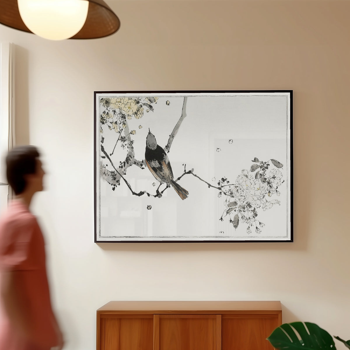 Framed art print of Bird on a Flowering Branch by Watanabe Seitei, in a slim black frame on a warm wall in a sunlit room