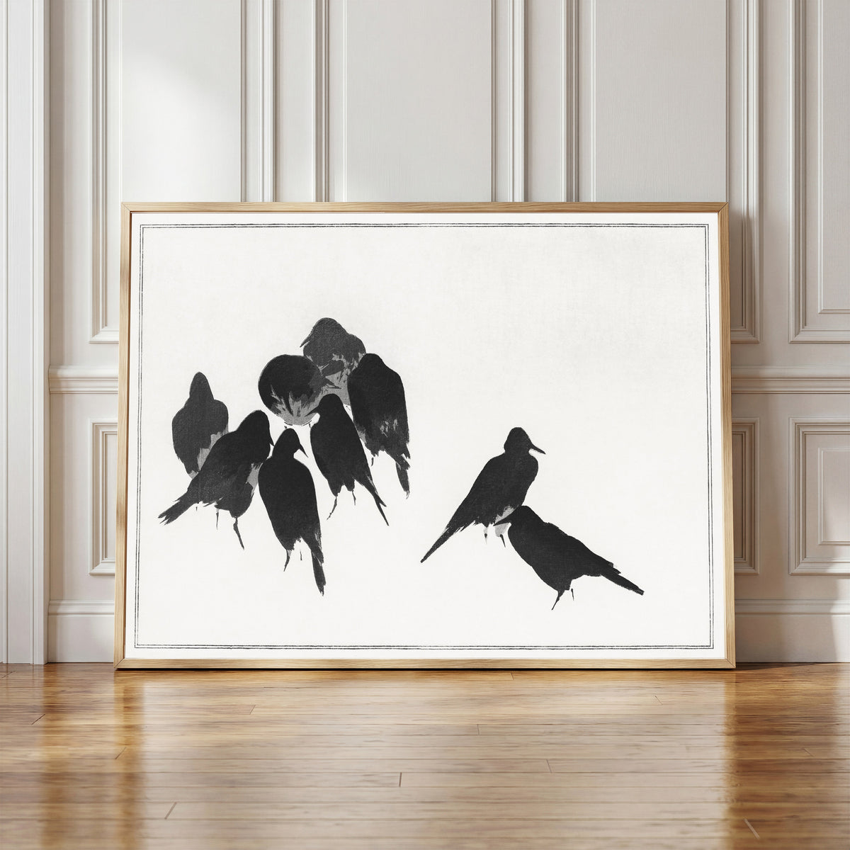 Framed art print of Japanese Crows by Watanabe Seitei, in a light wood frame leaning against a panelled white wall