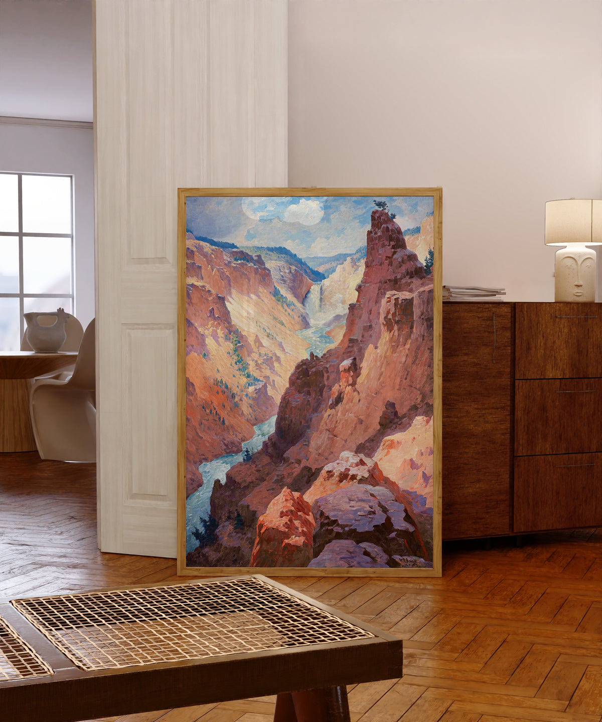 Framed art print of View of the Grand Canyon of the Yellowstone by William Robinson Leigh, in a light wood frame leaning in a warm room with a parquet floor
