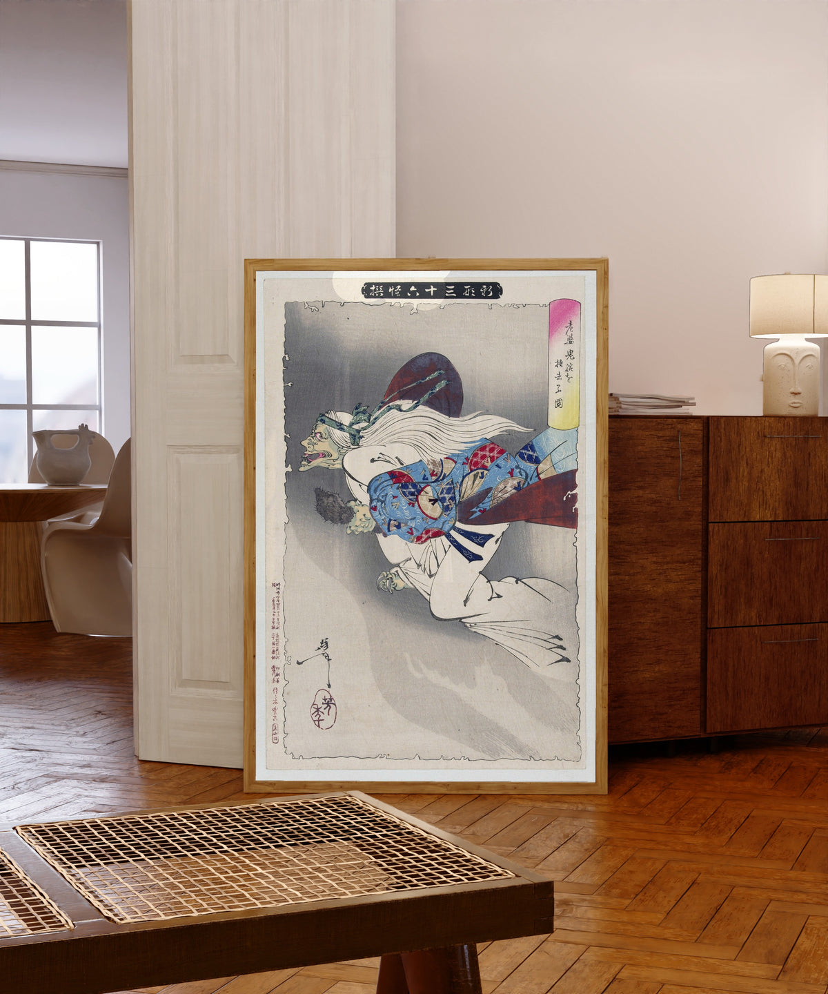 Framed art print of The Witch by Tsukioka Yoshitoshi, in a light wood frame leaning in a warm room with a parquet floor