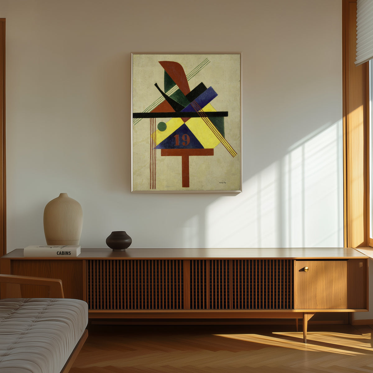 Framed art print of 19 by László Moholy-Nagy, in a thin light frame on a sunlit wall above a wooden sideboard