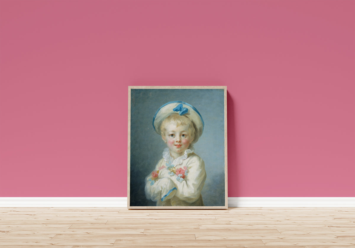 Framed art print of A Boy as Pierrot by Jean-Honoré Fragonard, in a light wood frame leaning on a pink wall above a wooden floor