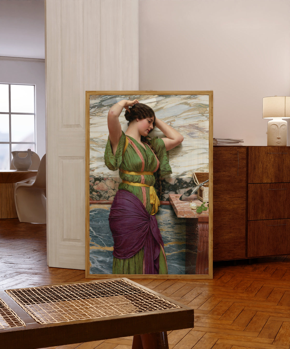 Framed art print of A Fair Reflection by John William Godward, in a light wood frame leaning in a warm room with a parquet floor