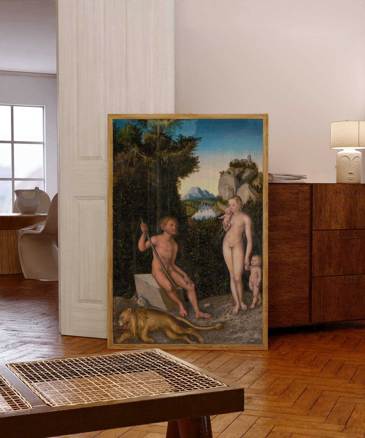 Framed art print of A Faun and His Family with a Slain Lion by Lucas Cranach the Elder, in a light wood frame leaning in a warm room with a parquet floor