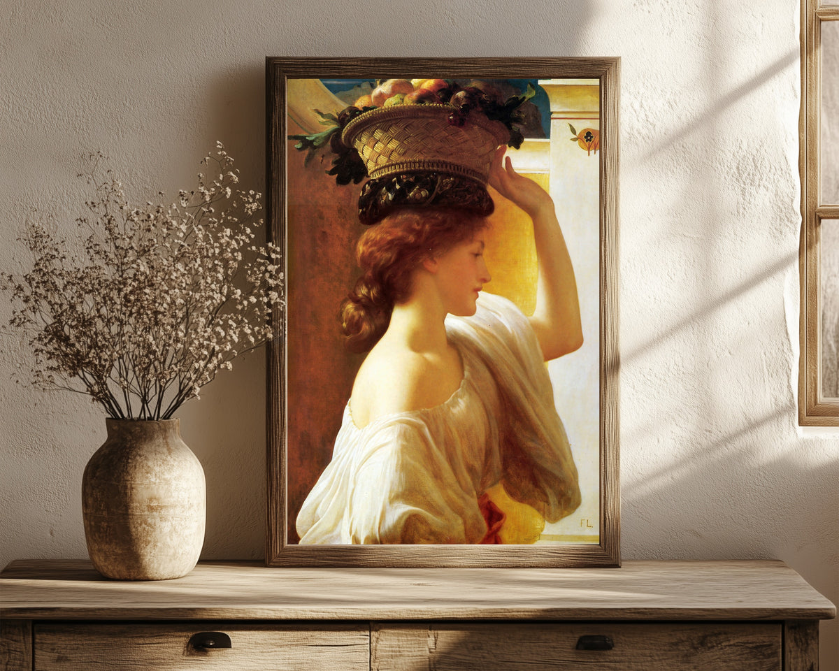 Framed art print of A Girl with a Basket of Fruit by Frederic Leighton, in a dark wood frame leaning on a rustic console beside dried flowers