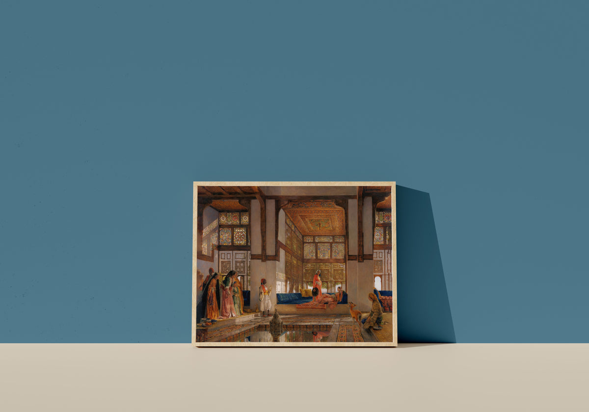 Framed art print of A Lady Receiving Visitors (The Reception) by John Frederick Lewis, in a light wood frame leaning on a blue wall