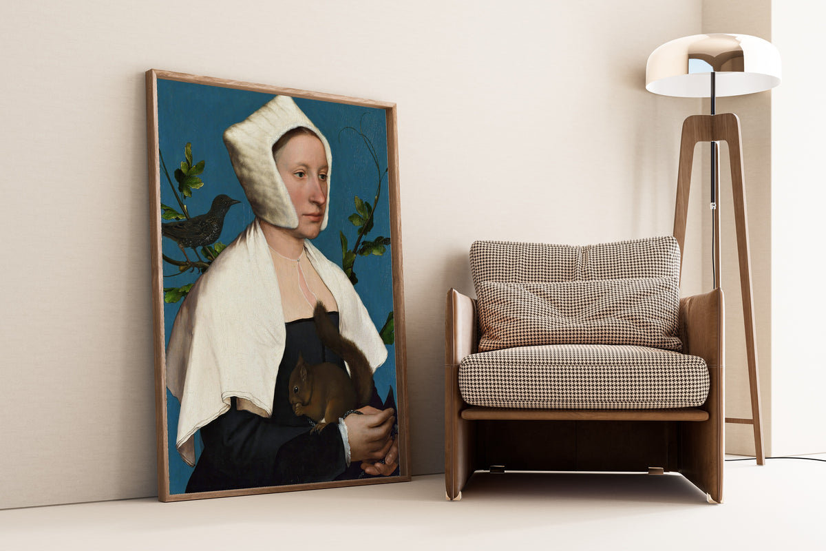 Framed art print of A Lady with a Squirrel and a Starling by Hans Holbein the Younger, leaning against a wall beside an armchair and a floor lamp