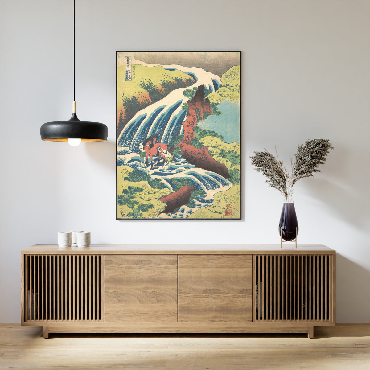 Framed art print of A Tour of the Waterfalls of the Provinces: The Waterfall Where Yoshitsune Washed His… by Katsushika Hokusai, above a slatted wood sideboard