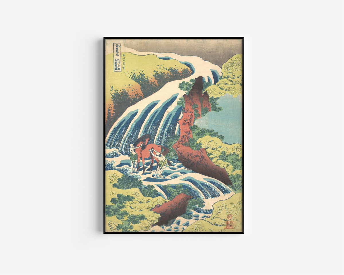 Framed art print of A Tour of the Waterfalls of the Provinces: The Waterfall Where… by Katsushika Hokusai, in a slim black frame on a plain white wall
