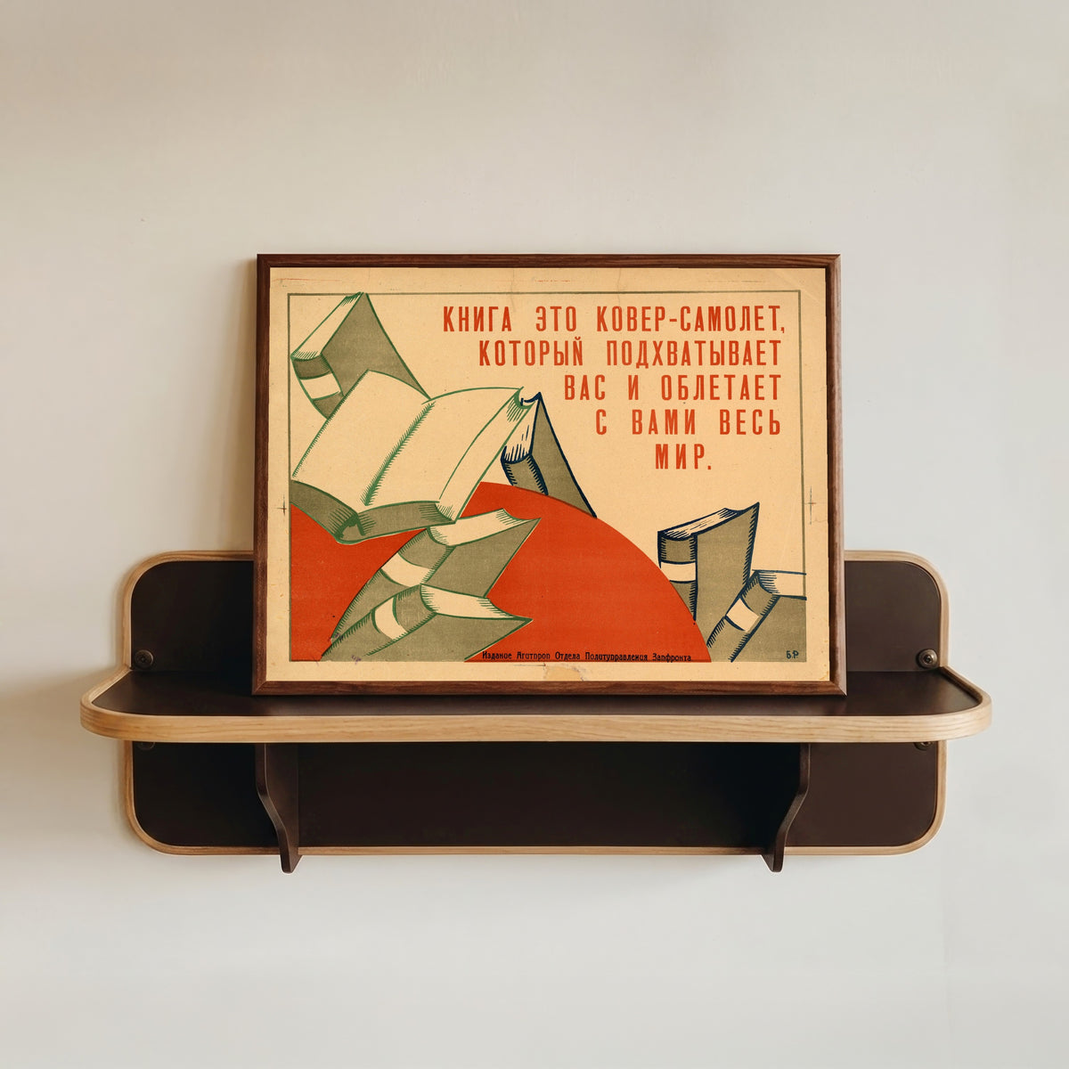 Framed art print of A book is a magic carpet that sweeps you up and carries you around the whole world, in a dark wood frame resting on a wall shelf