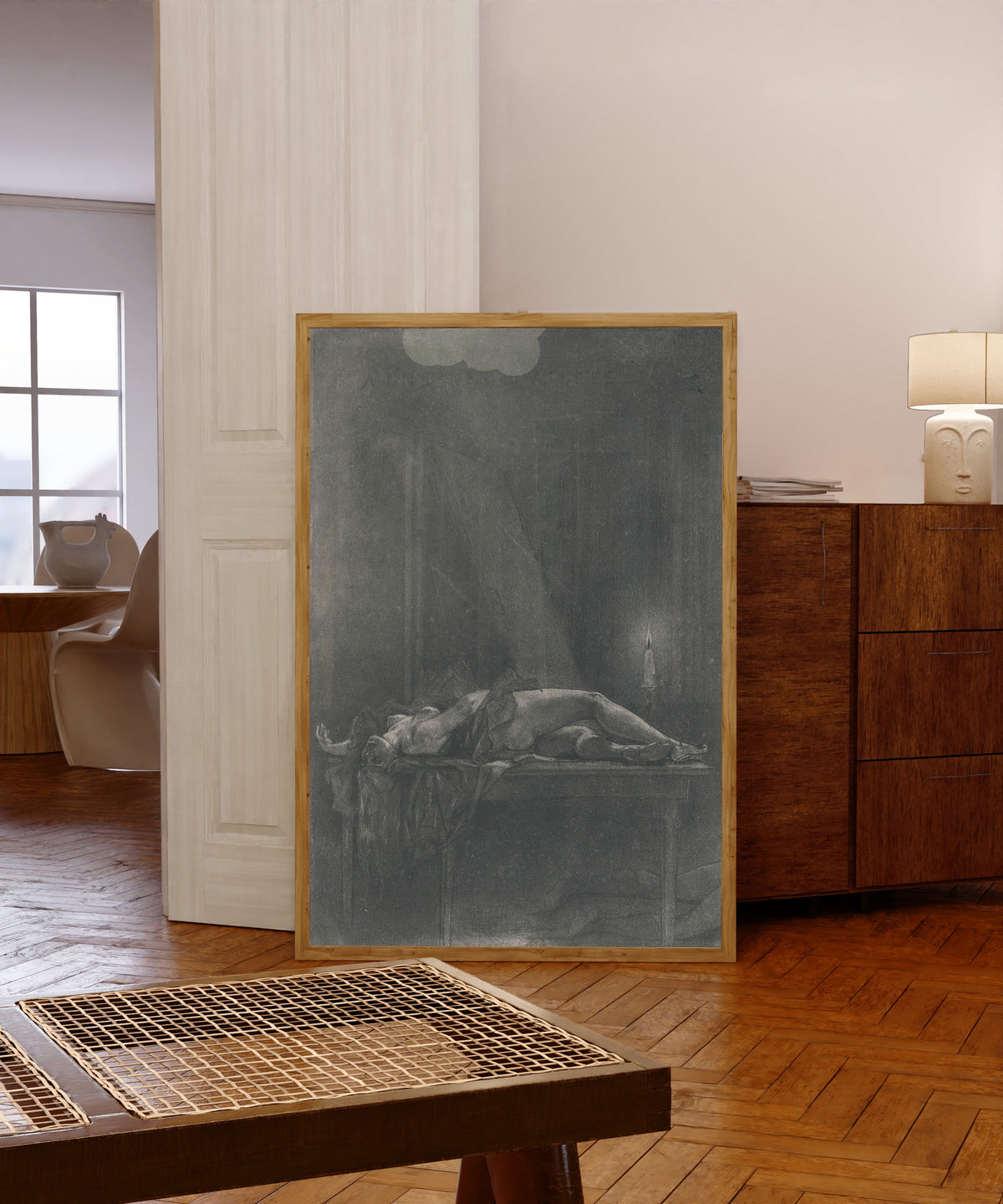 Framed art print of A un dîner d'athées (2nd state) by Félicien Rops, in a light wood frame leaning in a warm room with a parquet floor