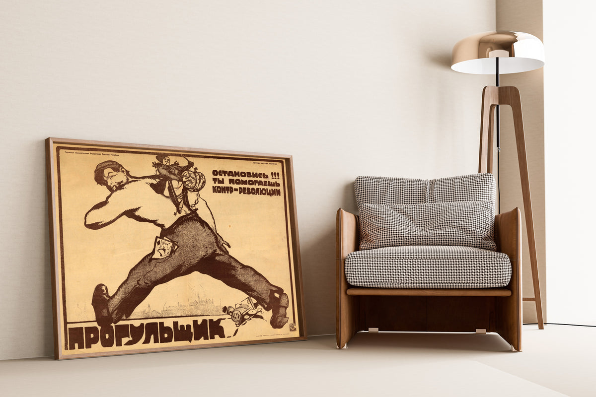 Framed art print of Absentee, Stop! You Are Helping the Counter-revolution! by Vasily Kostyanitsyn, leaning against a wall beside an armchair and a floor lamp