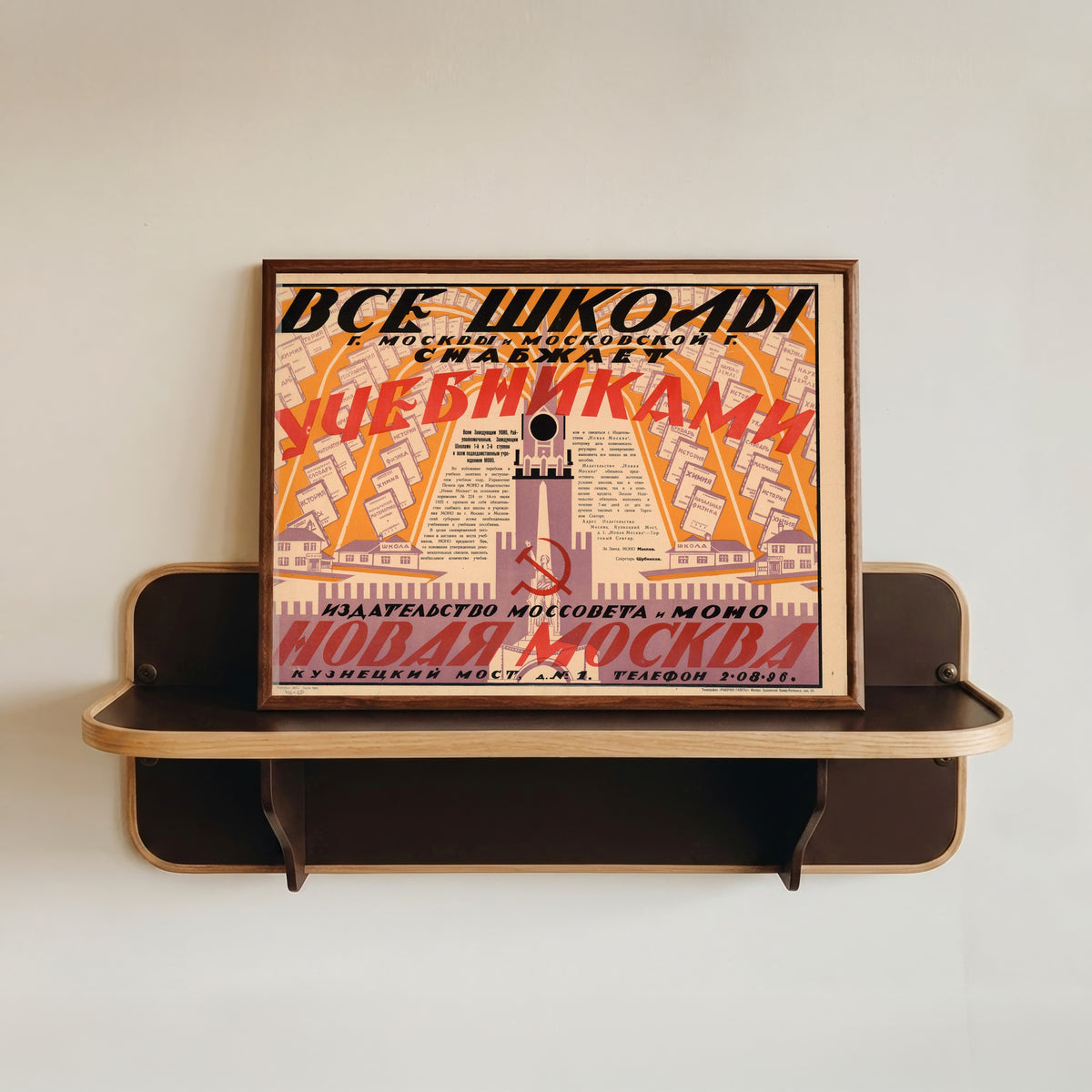 Framed art print of All schools of Moscow and Moscow Province are supplied with textbooks by the Mossovet…, in a dark wood frame resting on a wall shelf