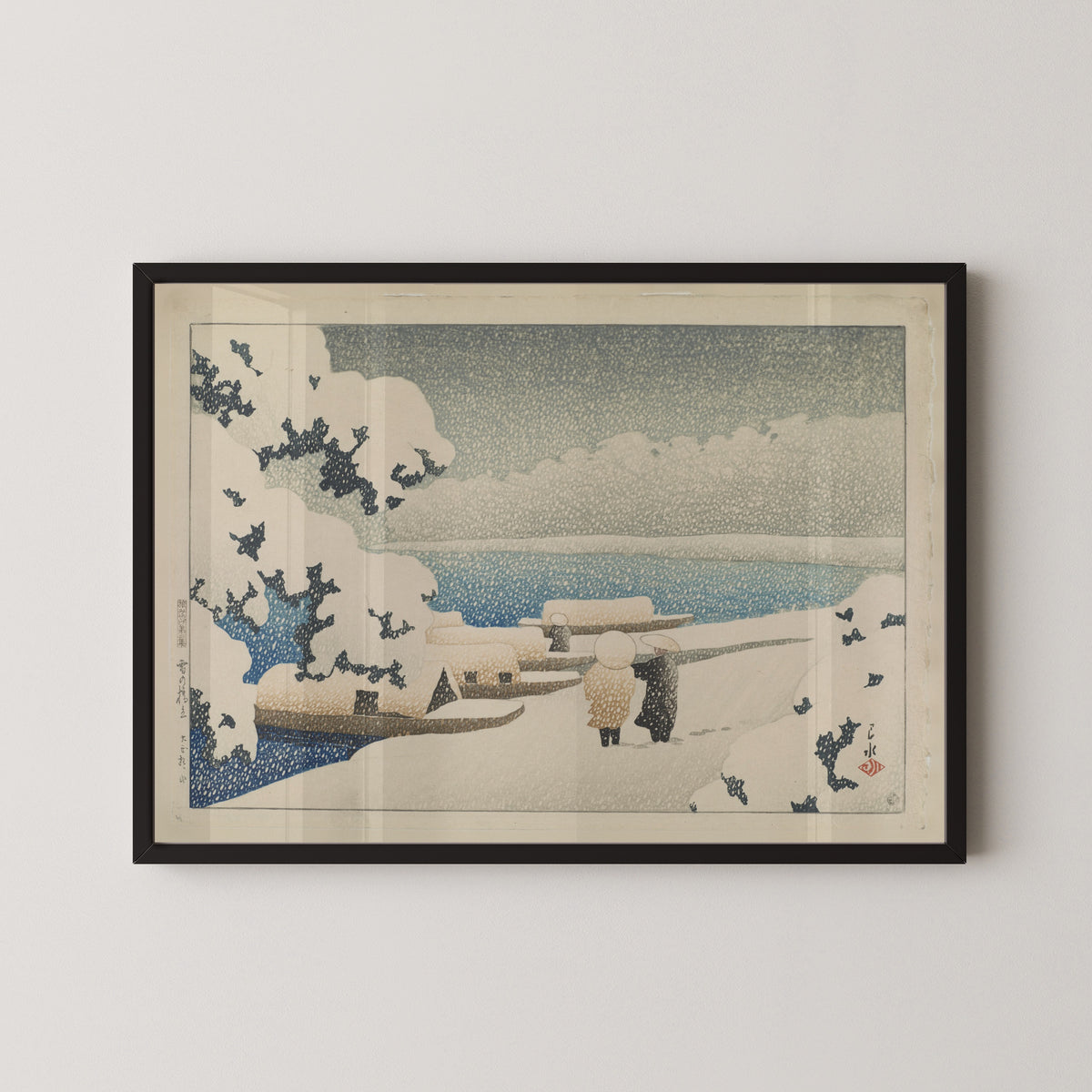 Framed art print of Amanohashidate in Snow by Kawase Hasui, in a black frame on a pale wall