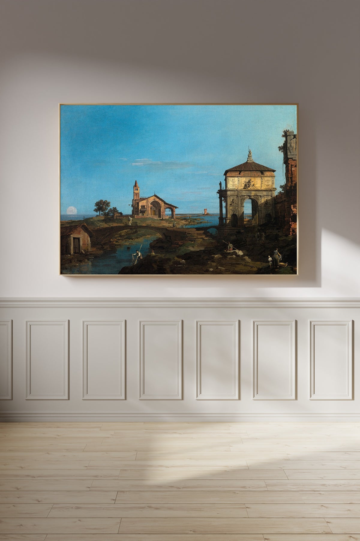 Framed art print of An Island in the Lagoon with a Gateway and a Church by Canaletto, on a panelled wall in afternoon light