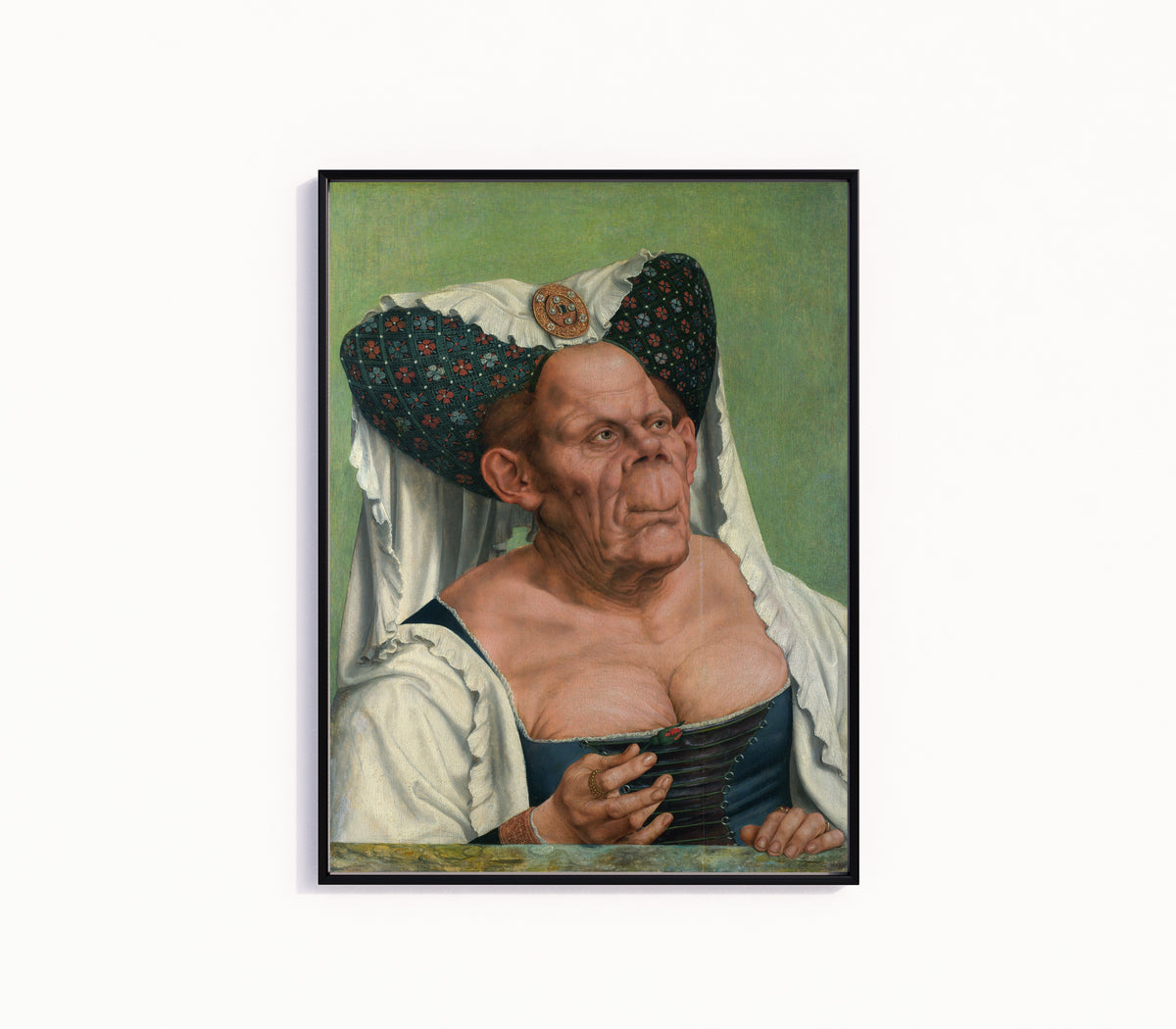 Framed art print of An Old Woman (The Ugly Duchess) by Quinten Massys, in a slim black frame on a plain white wall