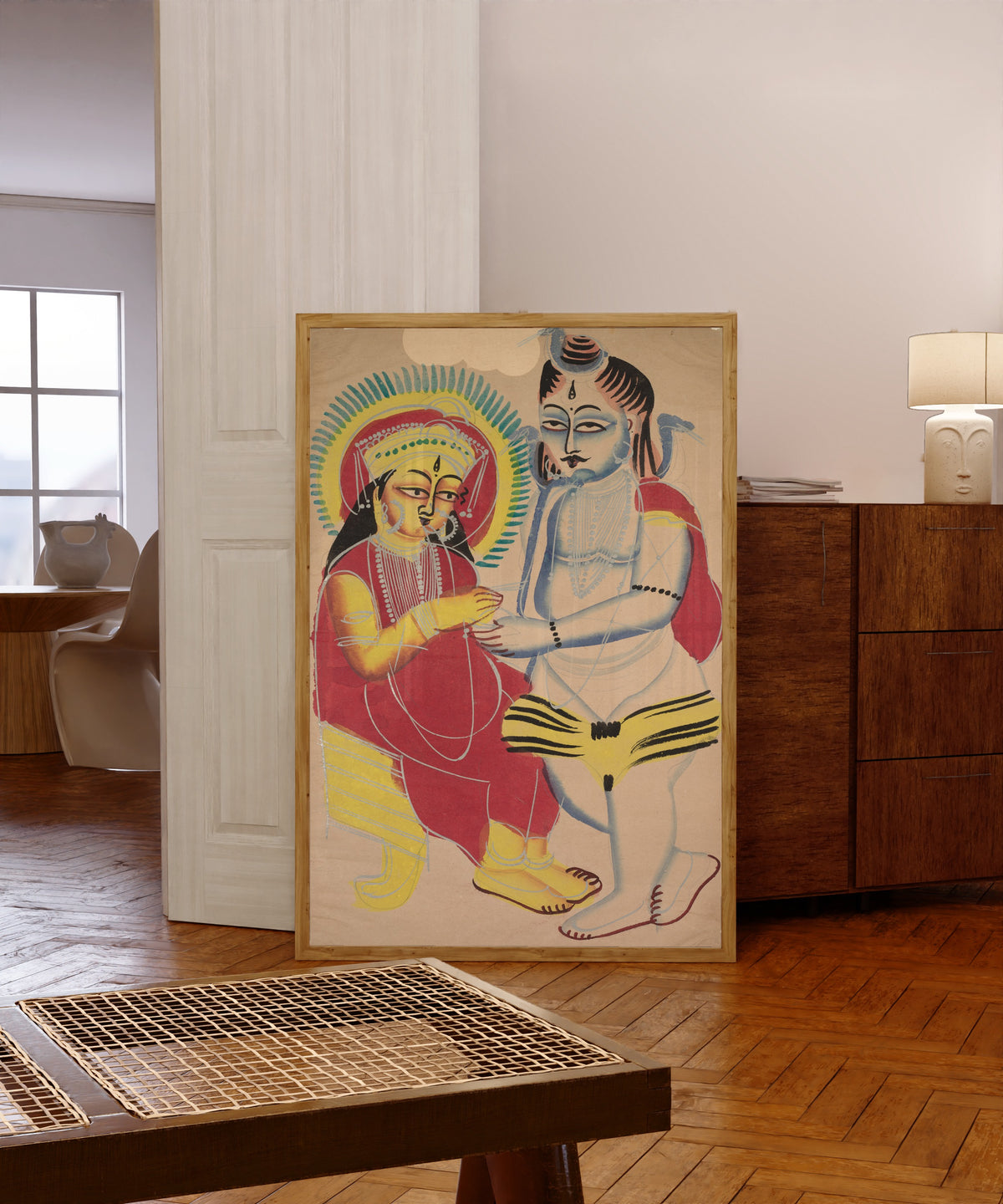 Framed art print of Annapurna and Shiva by Kalighat painter, in a light wood frame leaning in a warm room with a parquet floor