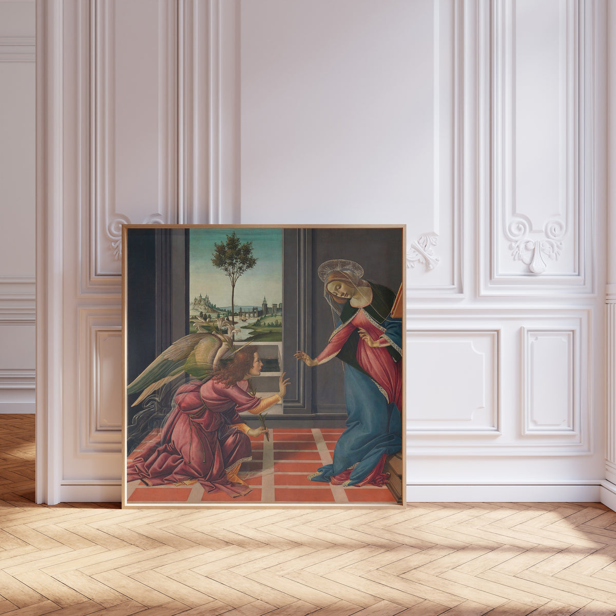 Framed art print of Annunciation by Sandro Botticelli, leaning against pale pink panelling on a herringbone floor