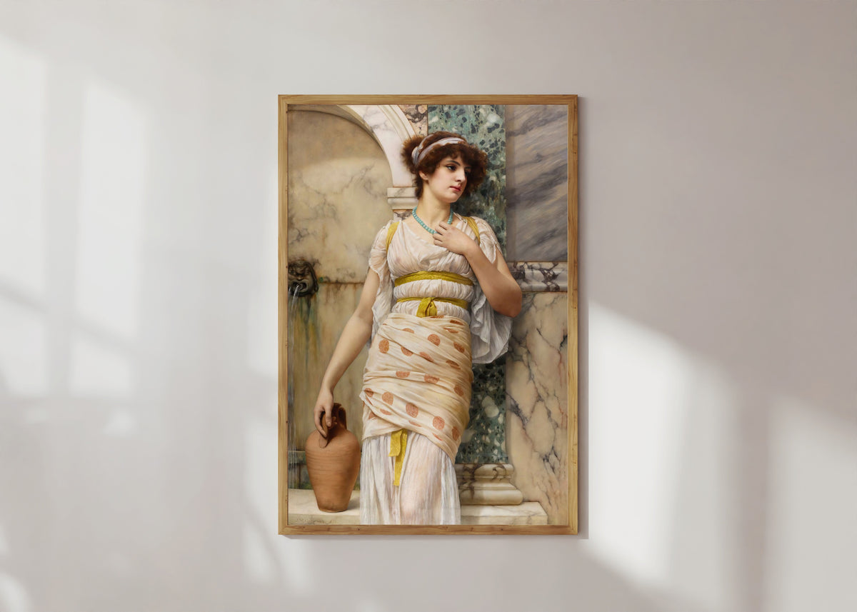Framed art print of At the Fountain by John William Godward, in a light wood frame on a sunlit white wall