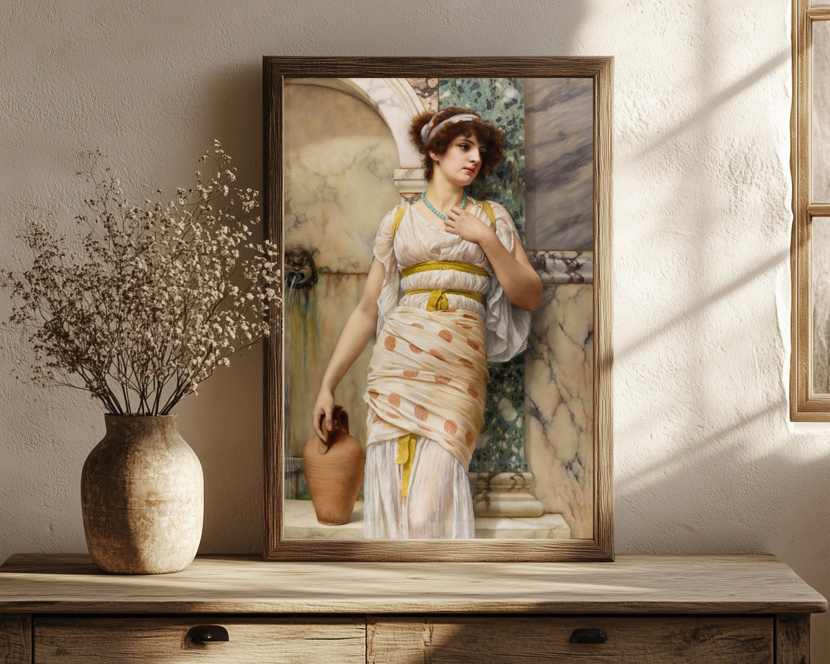 Framed art print of At the Fountain by John William Godward, in a dark wood frame leaning on a rustic console beside dried flowers