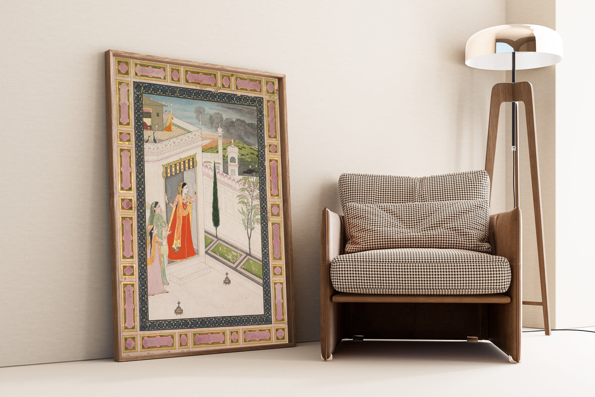 Framed art print of Augury of the crow (Vasakasajja Nayika) by Pahari school, leaning against a wall beside an armchair and a floor lamp