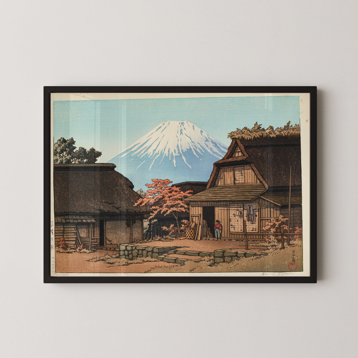 Framed art print of Autumn at Hirano by Kawase Hasui, in a black frame on a pale wall