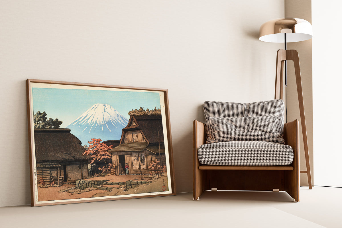 Framed art print of Autumn at Hirano by Kawase Hasui, leaning against a wall beside an armchair and a floor lamp