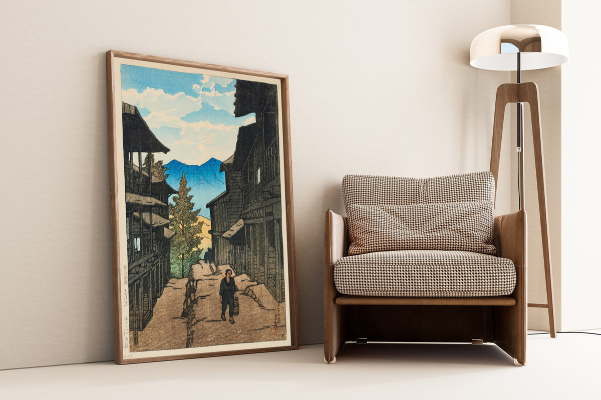 Framed art print of Autumn in Arayu, Shiobara by Kawase Hasui, leaning against a wall beside an armchair and a floor lamp