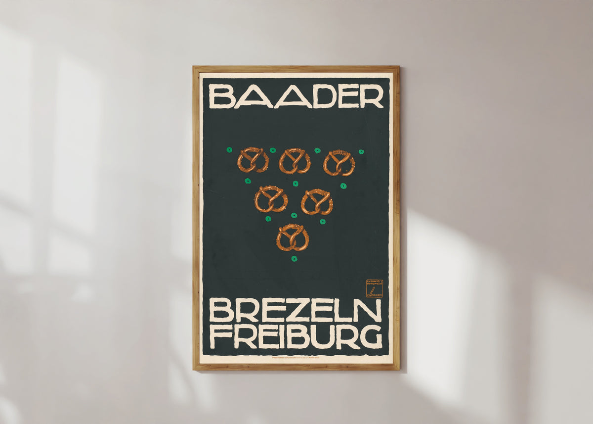 Framed art print of Baader Brezeln, Freiburg by Ludwig Hohlwein, in a light wood frame on a sunlit white wall