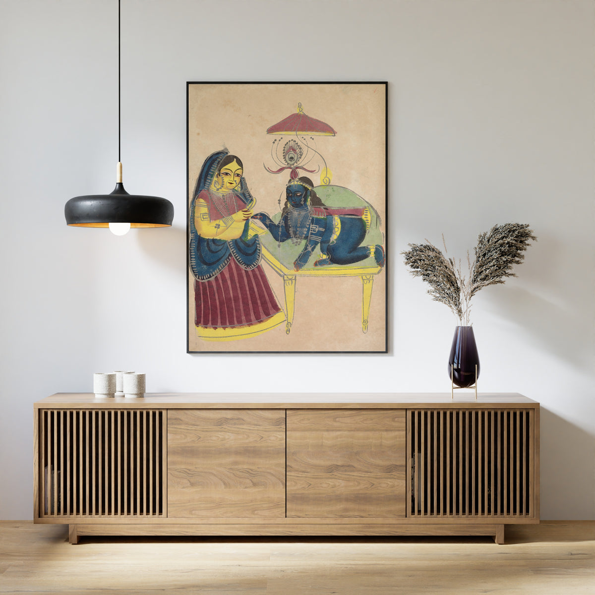 Framed art print of Baby Krishna Asking for Butter from Yashoda by Kalighat painter, above a slatted wood sideboard