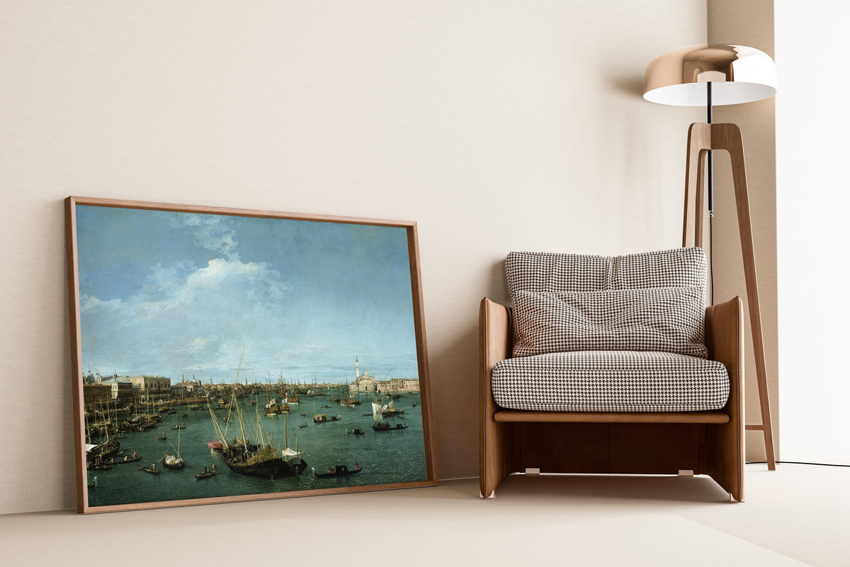 Framed art print of Bacino di San Marco, Venice by Canaletto, leaning against a wall beside an armchair and a floor lamp