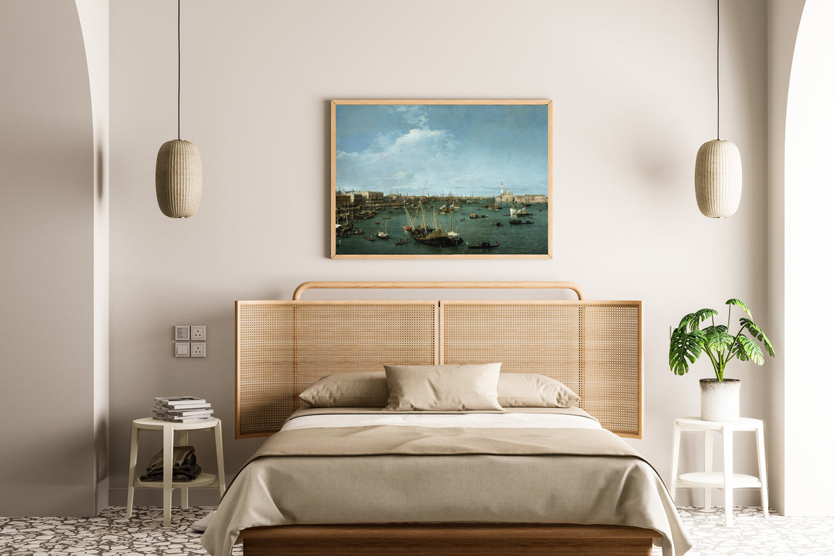 Framed art print of Bacino di San Marco, Venice by Canaletto, above a cane-headboard bed