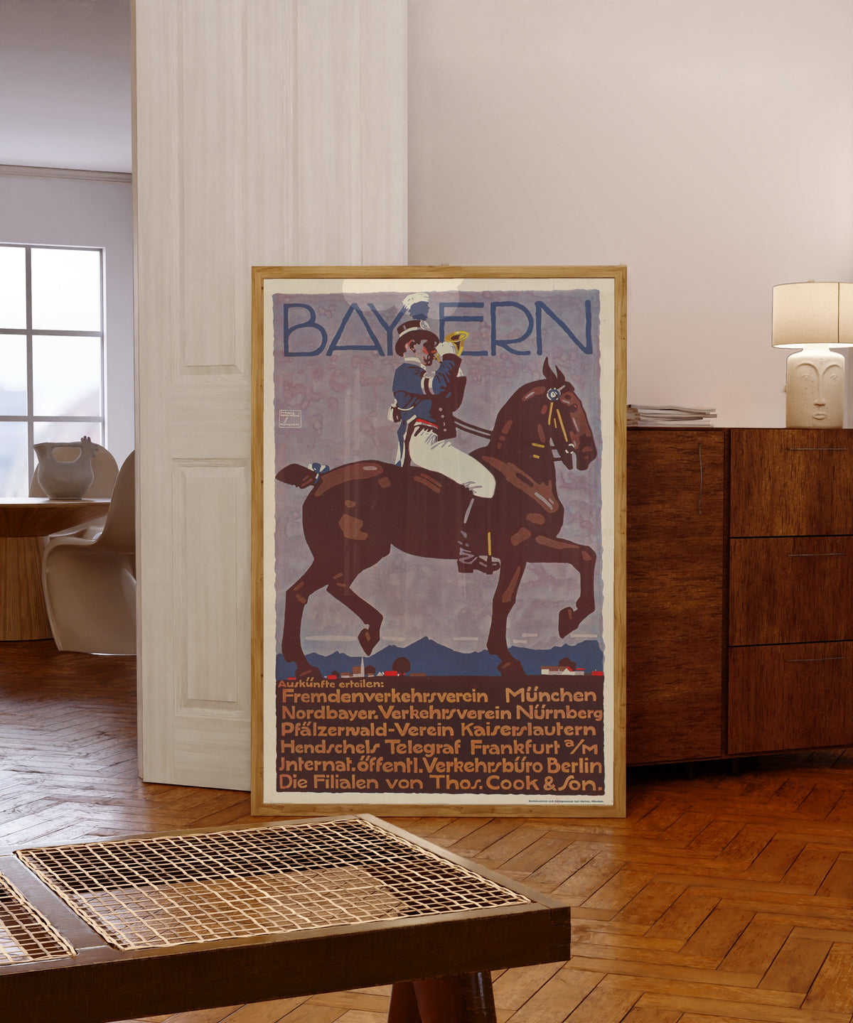 Framed art print of Bayern by Ludwig Hohlwein, in a light wood frame leaning in a warm room with a parquet floor