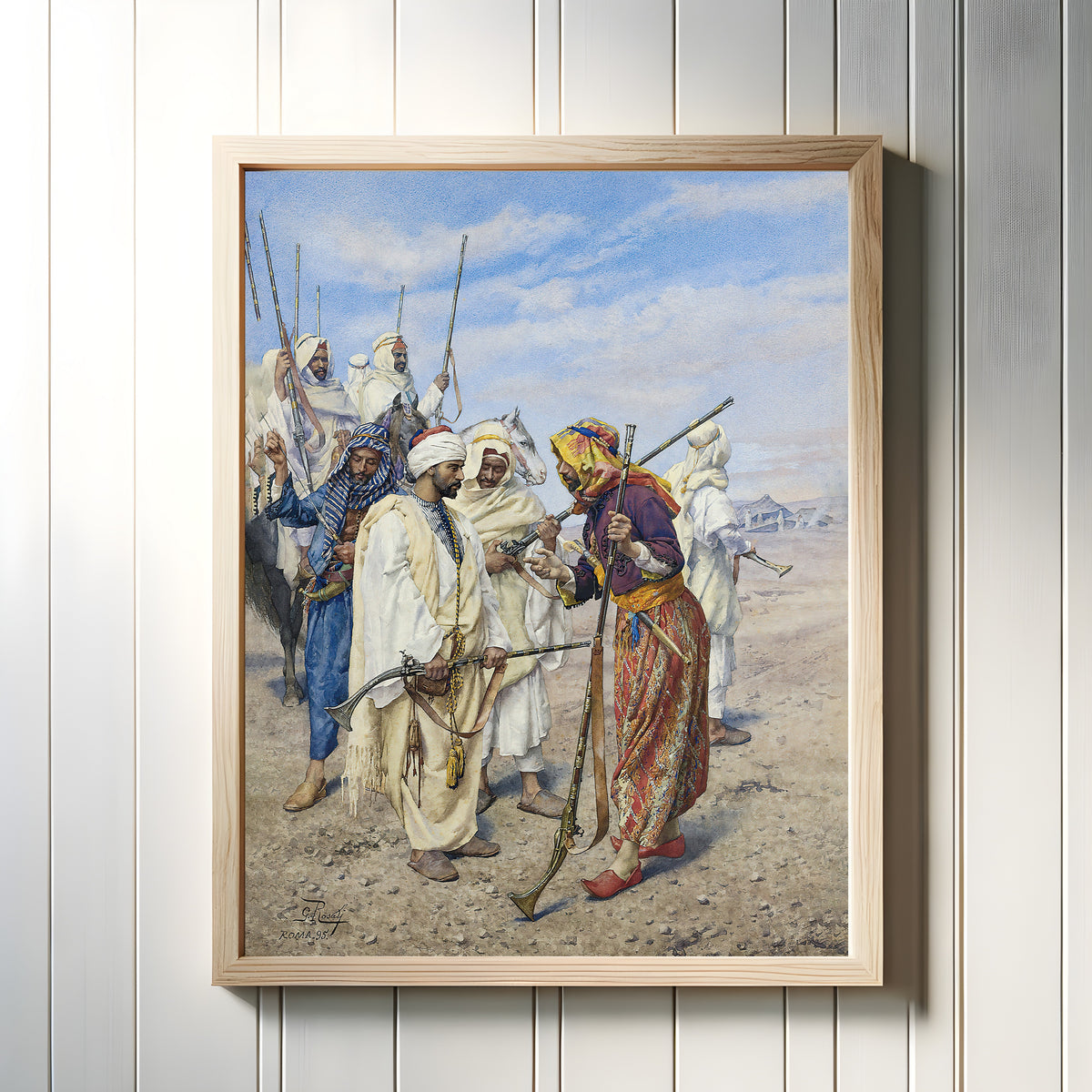 Framed art print of Bedouins Preparing a Raiding Party by Giulio Rosati, in a light wood frame on a white panelled wall