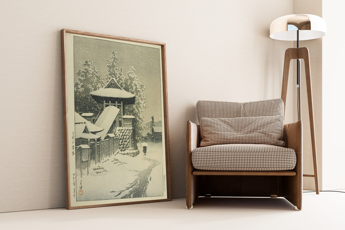 Framed art print of Bell Tower, Mount Koya by Kawase Hasui, leaning against a wall beside an armchair and a floor lamp