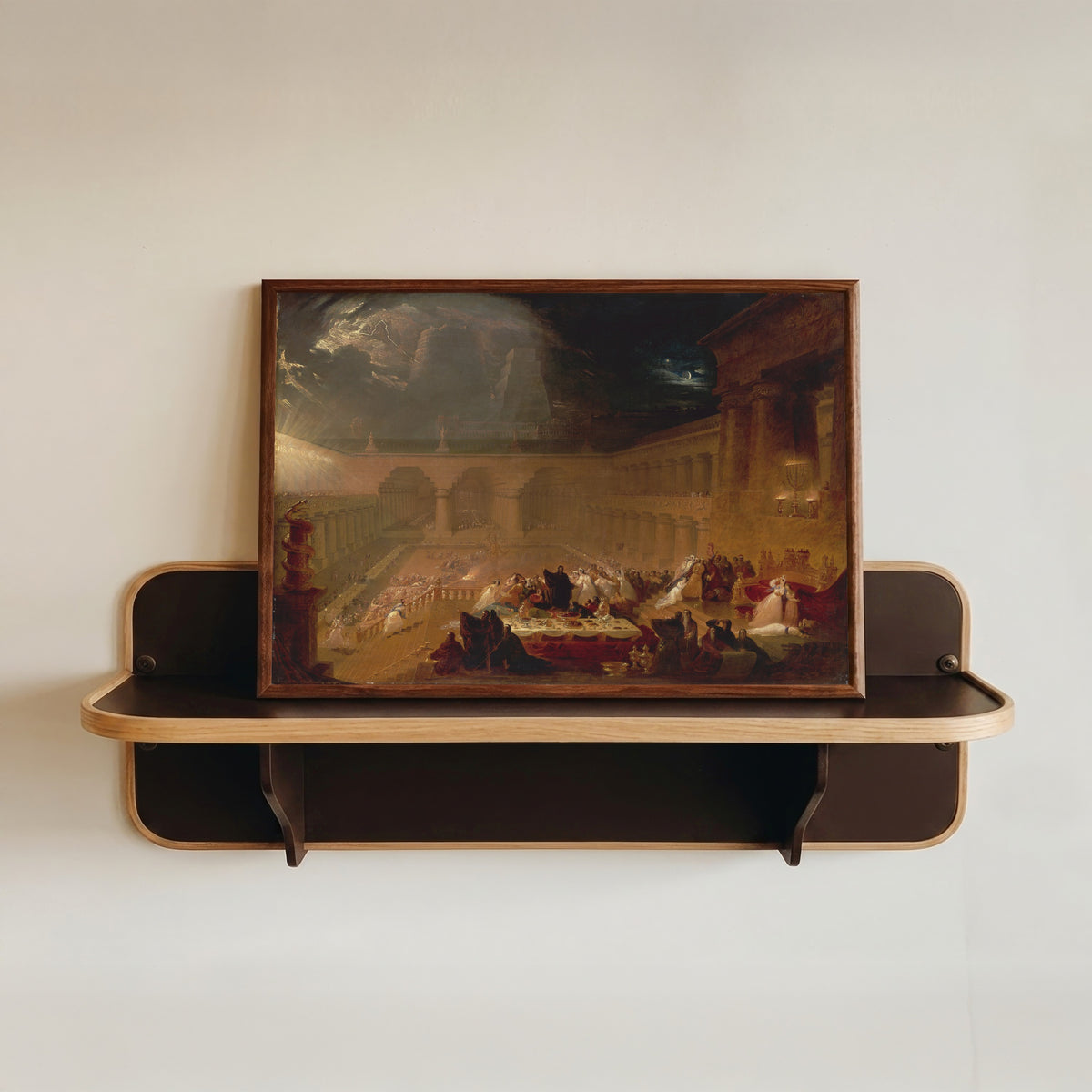 Framed art print of Belshazzar's Feast by John Martin, in a dark wood frame resting on a wall shelf