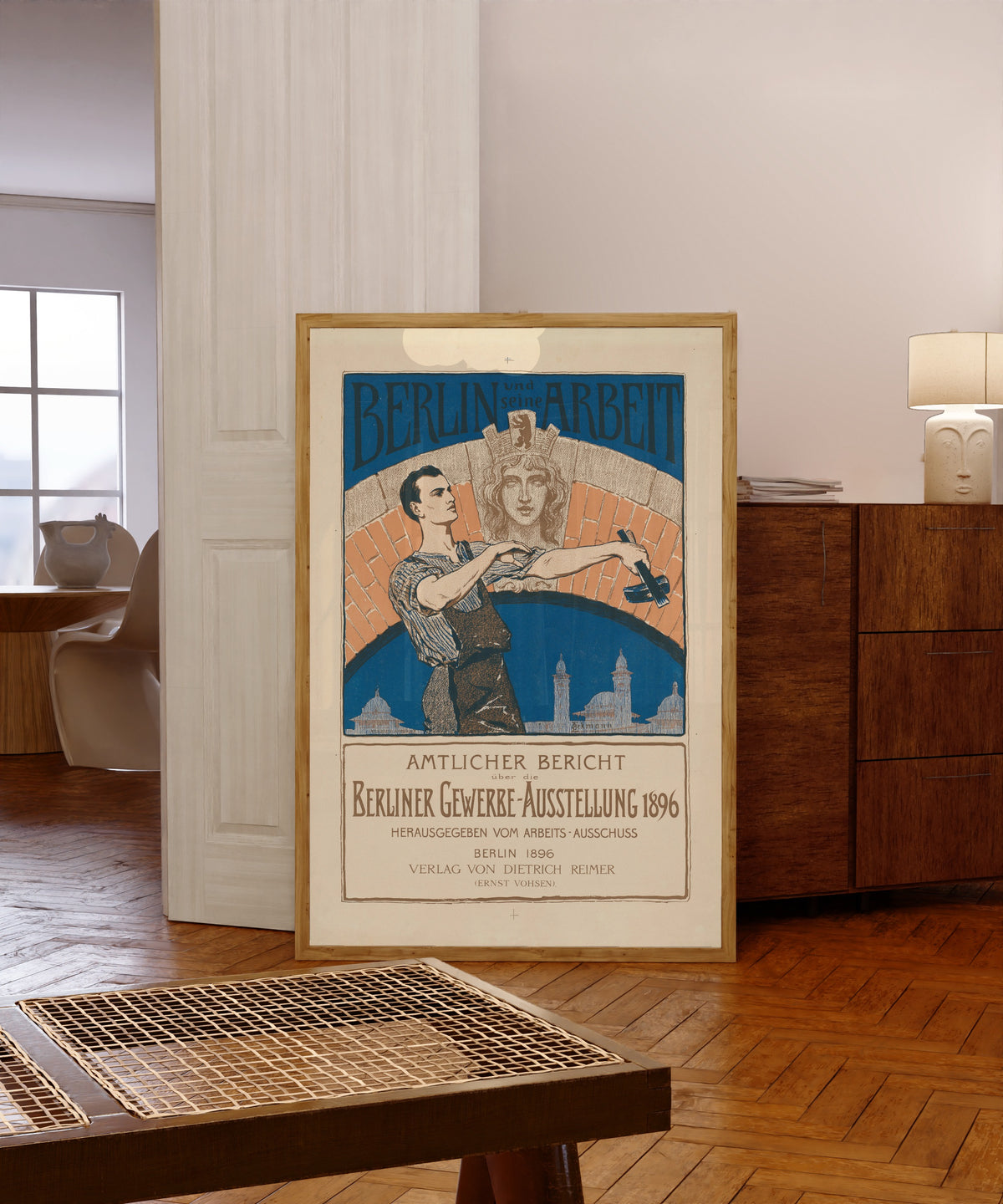 Framed art print of Berlin und seine Arbeit: Amtlicher Bericht über die… by Otto Eckmann, in a light wood frame leaning in a warm room with a parquet floor