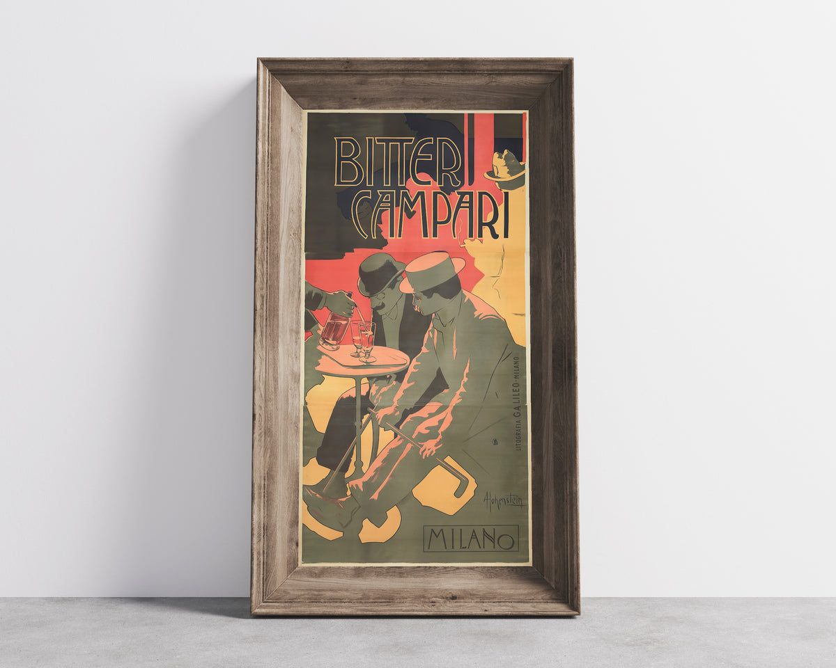 Framed art print of Bitter Campari by Adolfo Hohenstein, in a wide wooden frame leaning against a concrete wall