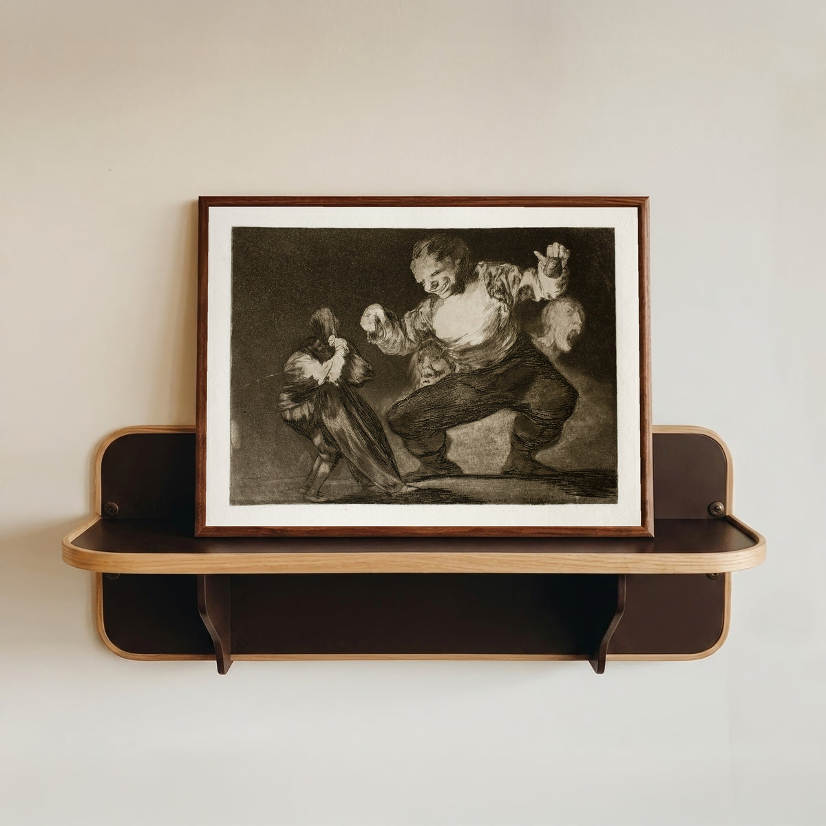 Framed art print of Bobalicón (Simpleton), from Los Disparates by Francisco de Goya, in a dark wood frame resting on a wall shelf
