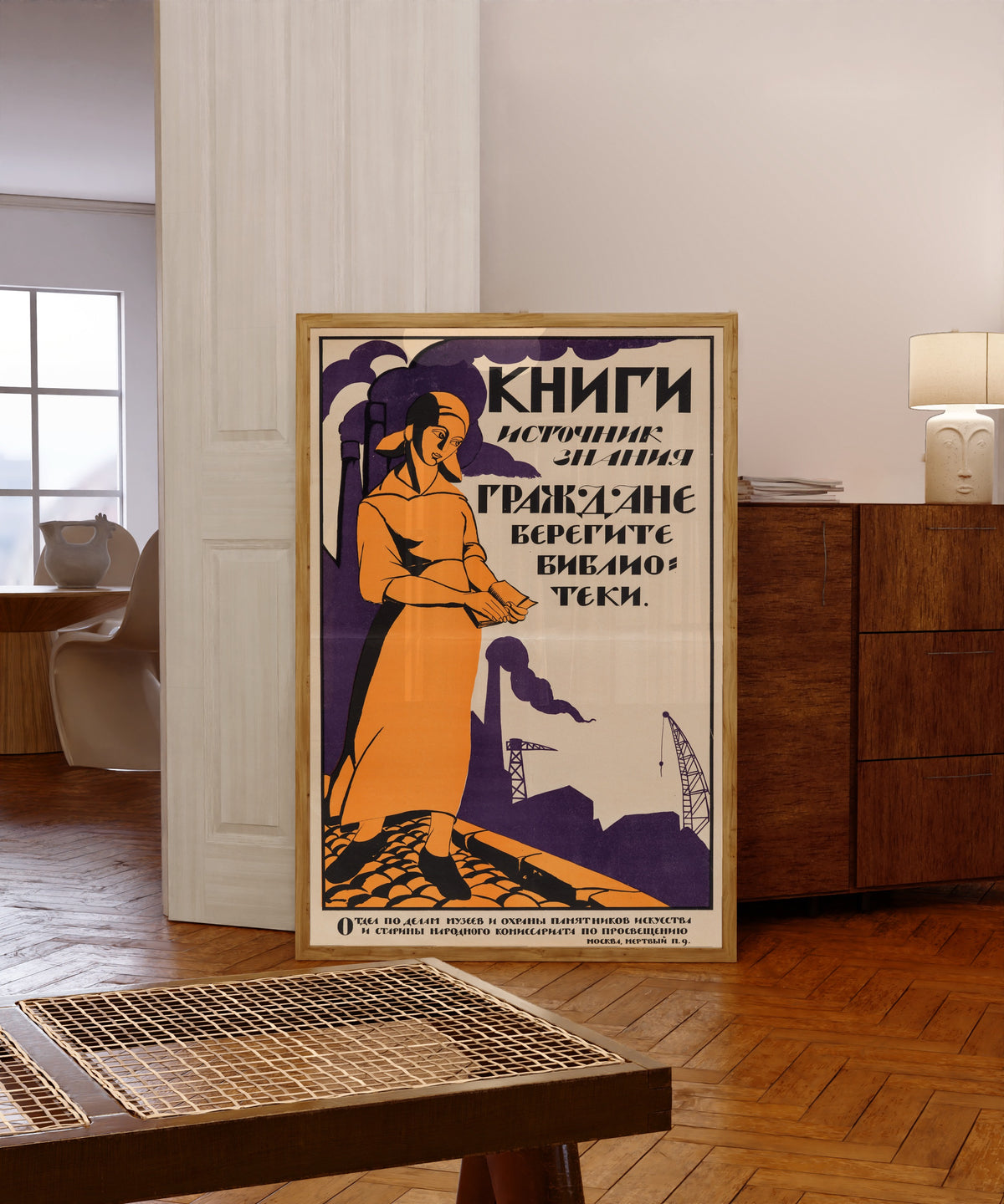 Framed art print of Books are the source of knowledge. Citizens, take… by Nikolai Kupreyanov, in a light wood frame leaning in a warm room with a parquet floor