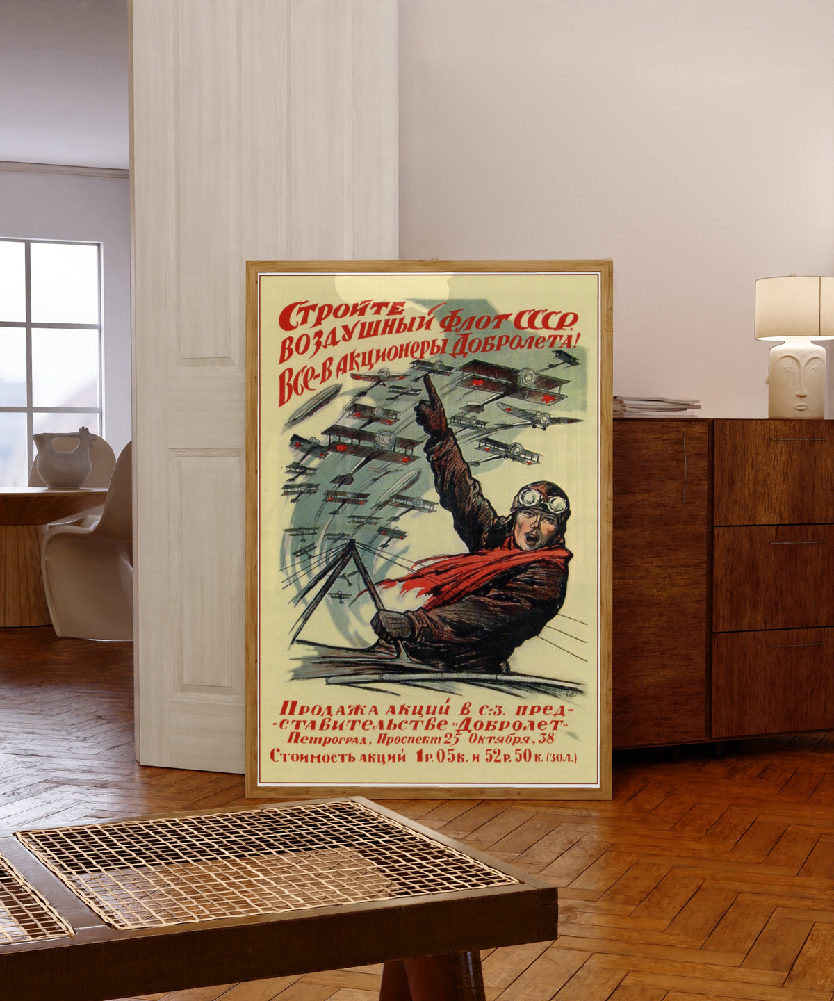 Framed art print of Build the air fleet of the USSR! Everyone, become a… by Ivan Simakov, in a light wood frame leaning in a warm room with a parquet floor