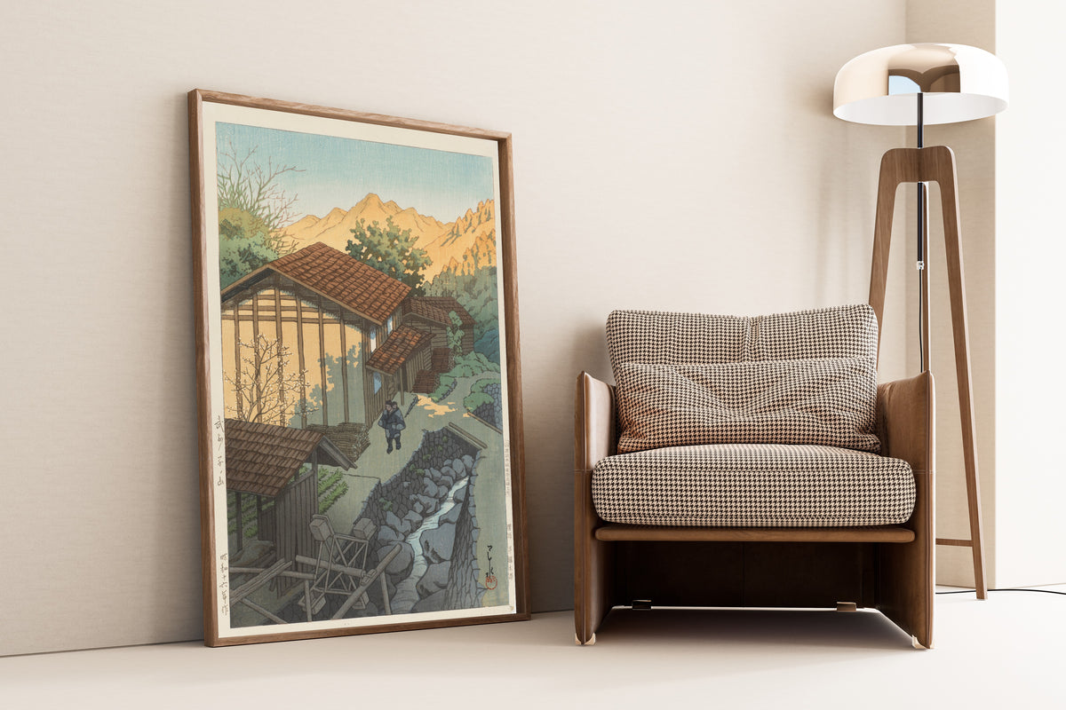 Framed art print of Bushu Nenoyama by Kawase Hasui, leaning against a wall beside an armchair and a floor lamp