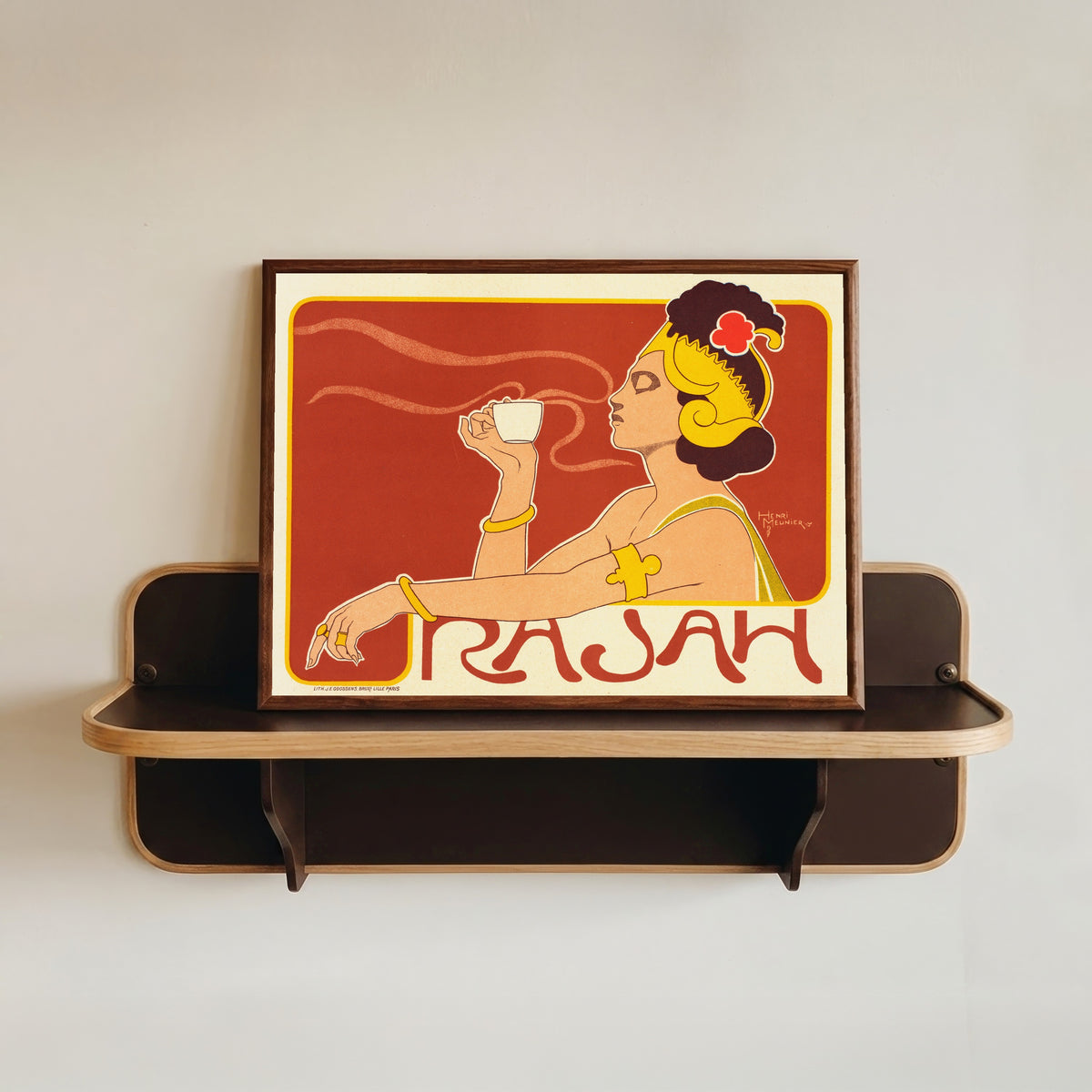 Framed art print of Café Rajah by Henri Meunier, in a dark wood frame resting on a wall shelf