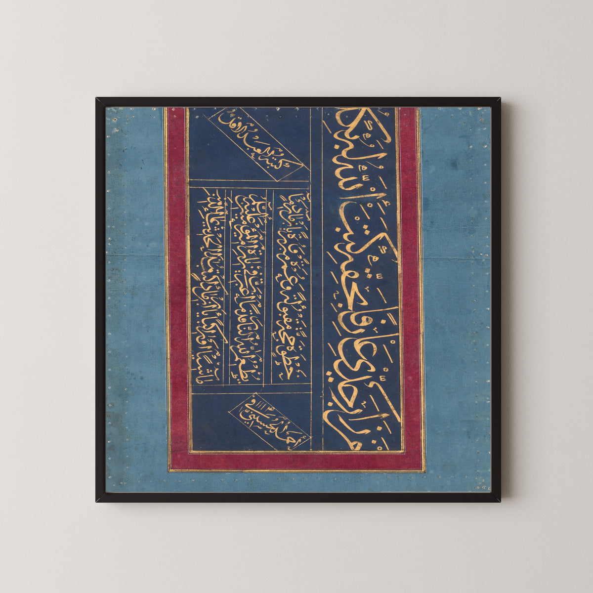 Framed art print of Calligraphy (Gold on Indigo) by Ahmad al-Husaini, in a black frame on a pale wall