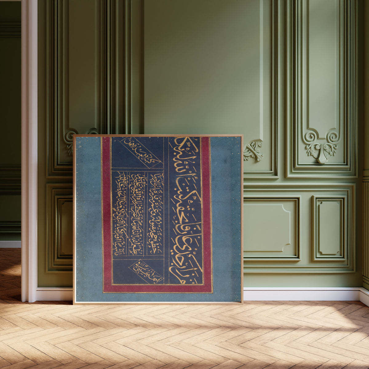 Framed art print of Calligraphy (Gold on Indigo) by Ahmad al-Husaini, leaning against olive-green panelling on a herringbone floor